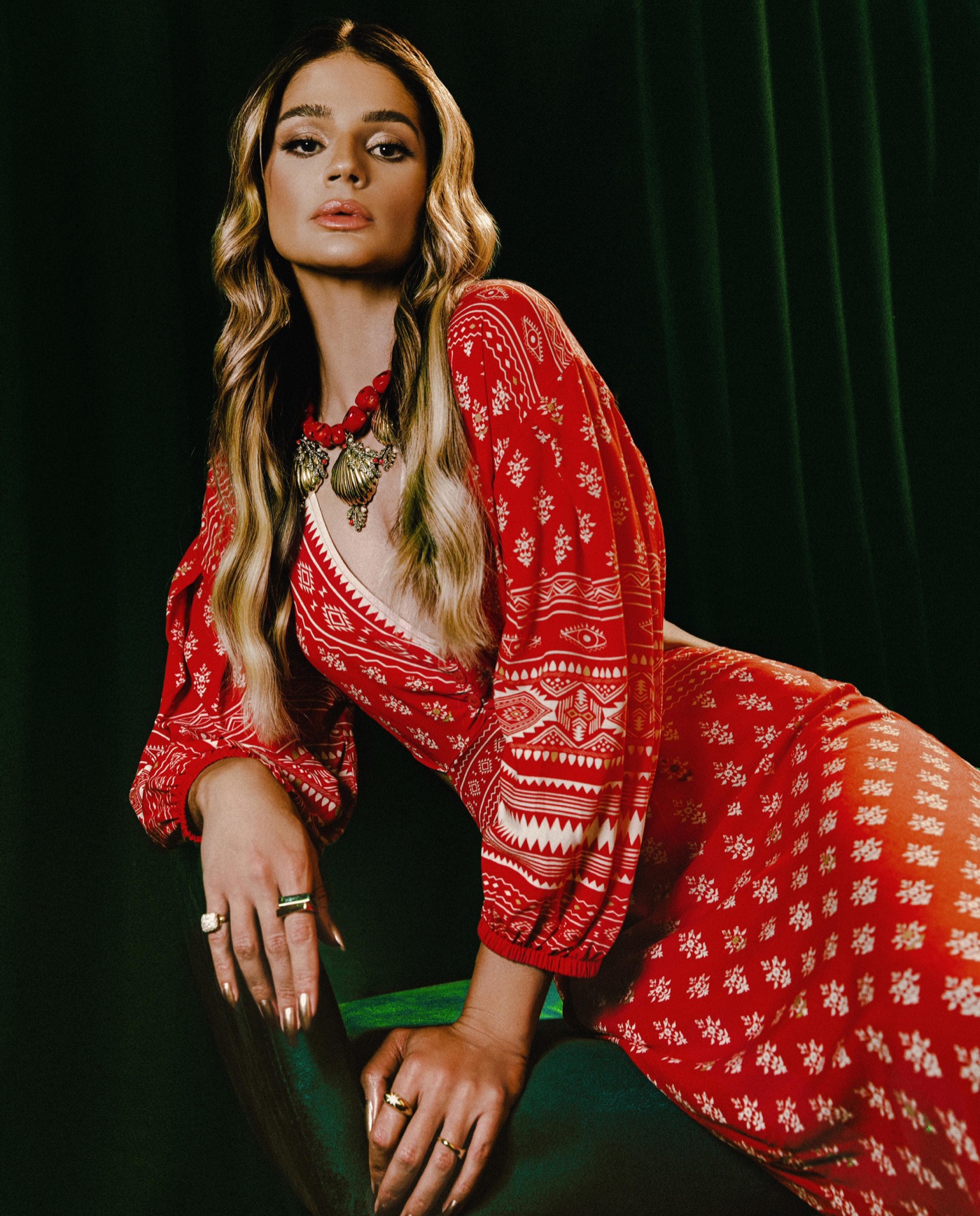 Thássia Naves em vestido vermelho estampado na cenografia verde da Colcci